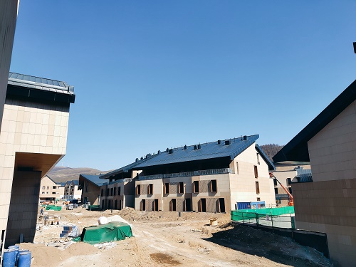 　　张家口冬奥村中国绿建最高标准，设计结合北方山地民居特色 　　4月18日下午，“百年京张路 筑梦冬奥行”网络主题活动来到北京冬奥会张家口赛区冬奥村，参观奥运村运动员公寓建设情况。冬奥村按照绿建三星标准建设，属中国最高标准。 　　基础装修已全部完成 规划设计结合了北方山地民居特色 　　张家口冬奥村建设用地19.76公顷，距离太子城高铁站0.5公里，距离京礼高速棋盘梁服务区1.5公里。赛时一期总建筑面积23.8万平方米，其中地上约13.5万平方米、地下约10.3万平方米。 　　冬奥村的规划设计结合了北方山地民居特色，共10个组团31栋楼，每个组团由3~4栋小楼围成一个院落。冬奥会赛时可提供房间1668间，总床位2737个。 　　张家口冬奥村分为三个功能区：居住区、广场区和运行区。居住区主要是为冬奥村居民的住宿、办公和医疗空间;广场区是冬奥村举办仪式的地方，还设有一些商业设施，是访客参观的主要区域;运行区是冬奥村工作人员办公的场所。 　　张家口奥体公司工程师陈科旭告诉记者，冬奥村按照绿建三星标准建设，属中国最高标准。目前冬奥村基础装修已全部完成，正在进行室外管道建设和景观打造。 　　符合绿色办奥的理念，又能充分满足冬奥会的需求 　　据介绍，张家口冬奥村样板间的设计遵循绿色办奥理念，户型以适应全季山地度假特色的户型为主;户型大小适中，厨房、餐厅、卫生间洗浴、客厅、卧室等功能都有配备;赛时为运动员提供温馨舒适的居住环境，赛后作为滑雪公寓使用。 　　房间内以明亮的浅色调为主，墙面选用暖白色耐擦洗壁纸，地面选用原木色地板，材料生态环保。冬奥村窗户密封保温好，适应崇礼严寒气候条件。房间内供暖采用电供热，地板下满铺碳纤维发热电缆，电能为张家口的可再生能源风电，绿色环保。 　　值得一提的是，张家口冬奥村按照中国最高的绿建三星标准进行建设，通过采取一系列节地、节能、节材、节水措施，使冬奥村既符合绿色办奥的理念，又充分满足冬奥会的需求，为运动员、教练员和随队官员们提供一个环保、科技、温馨、舒适的家。 　　以上就是建筑界热点频道为大家带来的“张家口冬奥村中国绿建最高标准，设计结合北方山地民居特色 ”信息，建筑界热点频道也将持续关注相关建筑行业热点资讯，欢迎关注我们，关注建筑界行业热点~.jpg